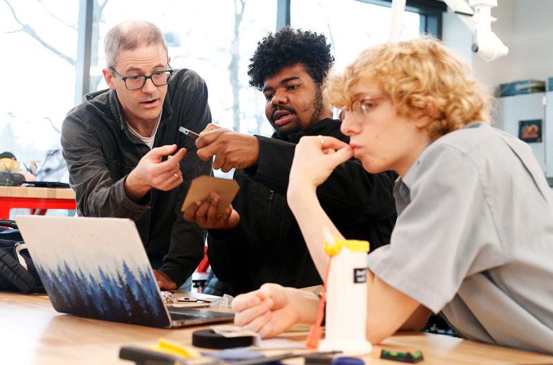 Students in a classroom with 的ir professor working over a laptop